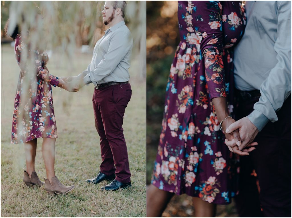 couple holds hands under a willow tree in floral dress