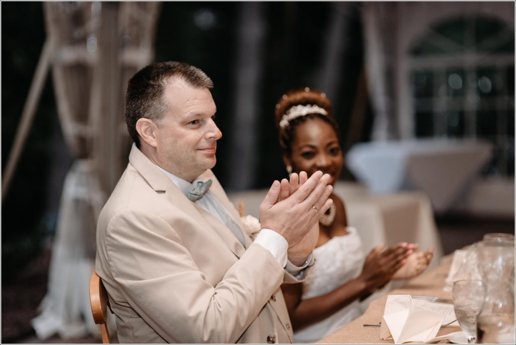 groom claps with a tear in his eye at wedding reception