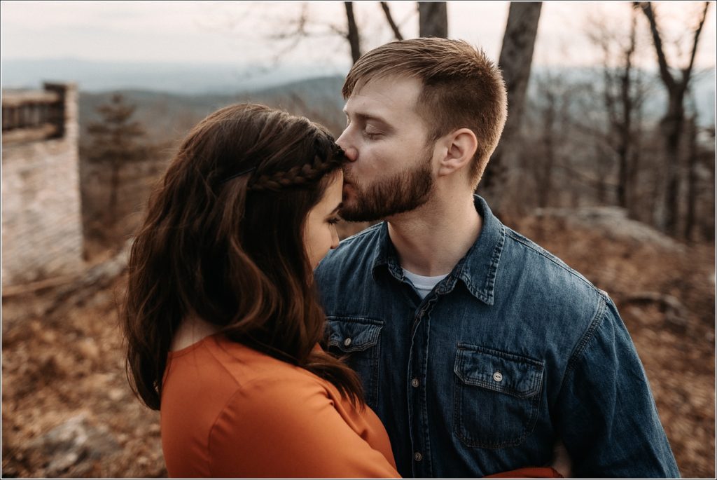 man kisses womans forehead at middletown overlook in burnt orange dress and blue jean button down
