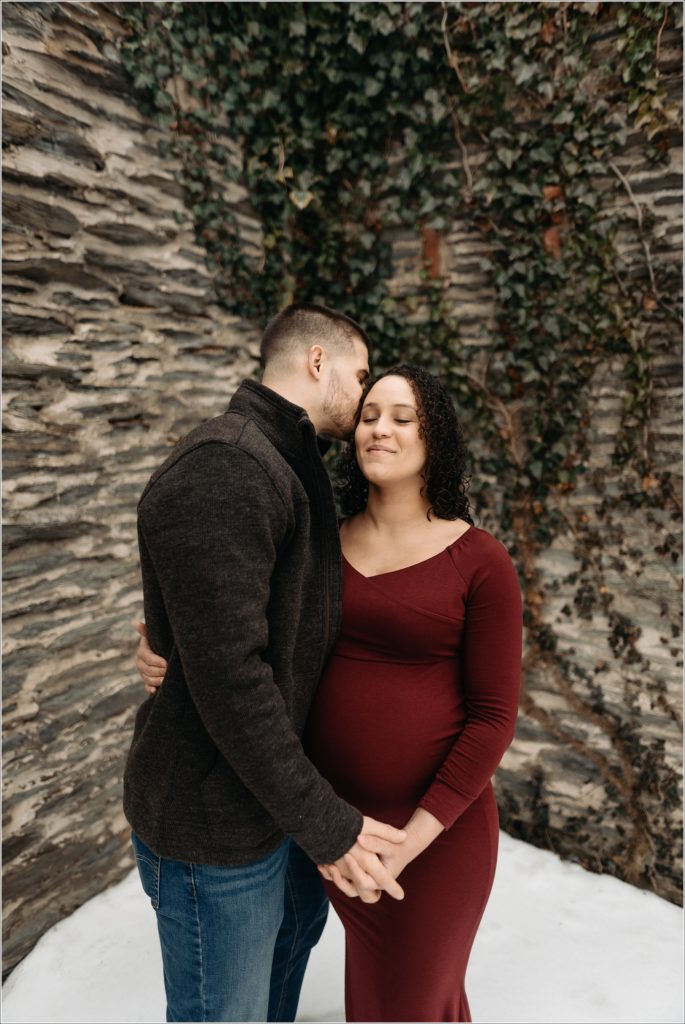 pregnant woman and husband in long red maternity dress with maryland maternity photographer at ruins at st.johns in harpers ferry