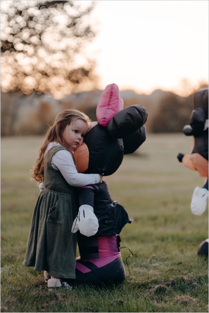 little girl in green jumper hugs minnie mouse inflatable