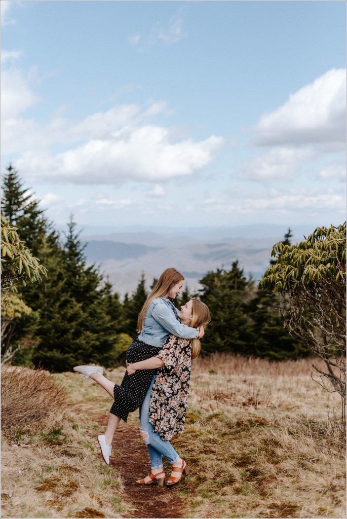 woman picks up woman with mountain backdrop on roan mountain carver's gap