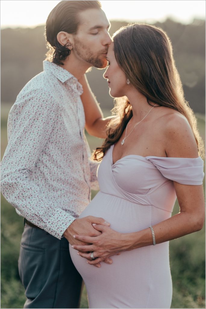 Pregnant woman in lilac maternity dress in Urbana Villages field with her husband