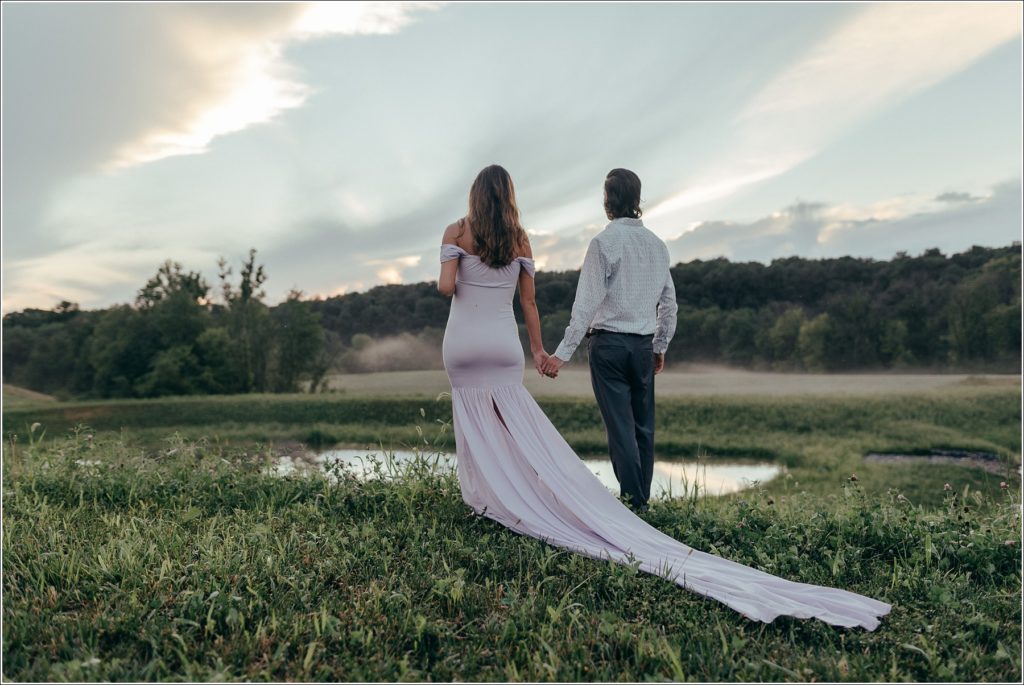 Pregnant woman in lilac maternity dress in Urbana Villages field with her husband and a rose