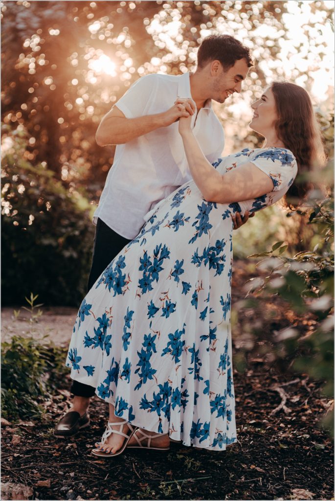 Engaged Couple snuggles by the Georgetown Waterfront in white linen outfits with blue flowers