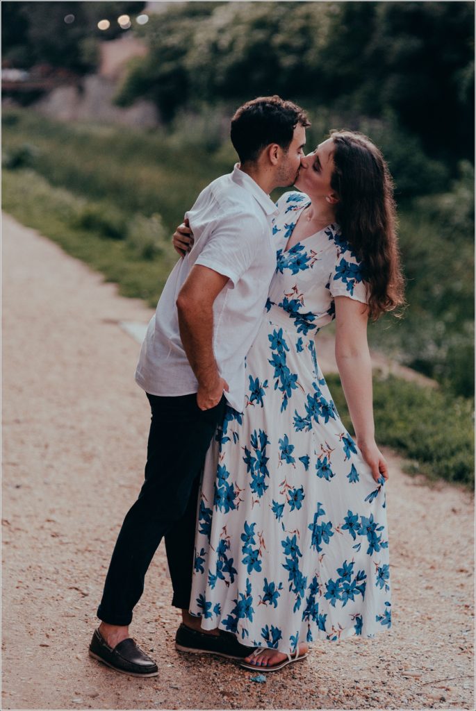 Fiances kiss by the C&O canal in white linen summer outfits