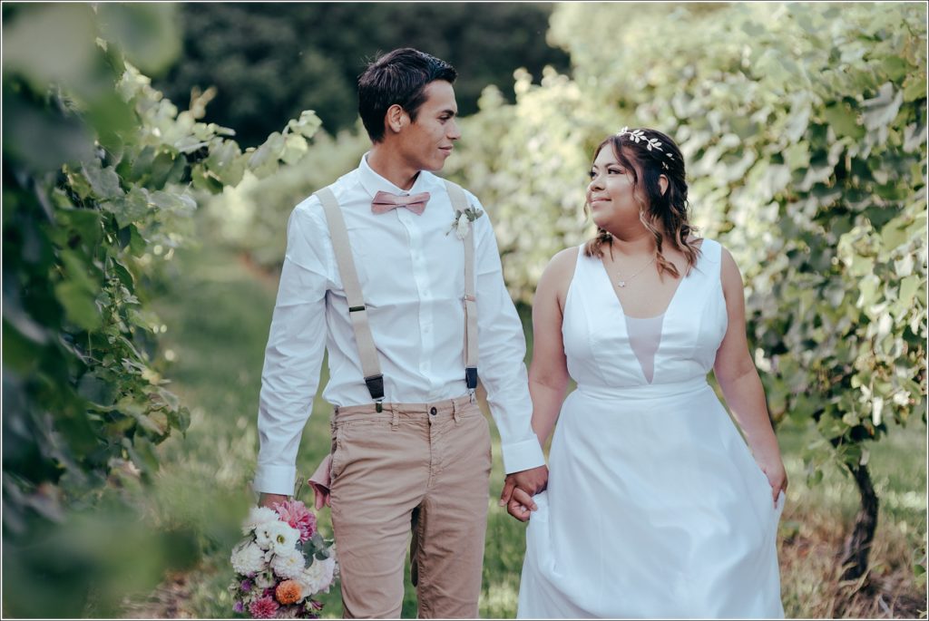 bride and groom walk in Orchard House vineyard