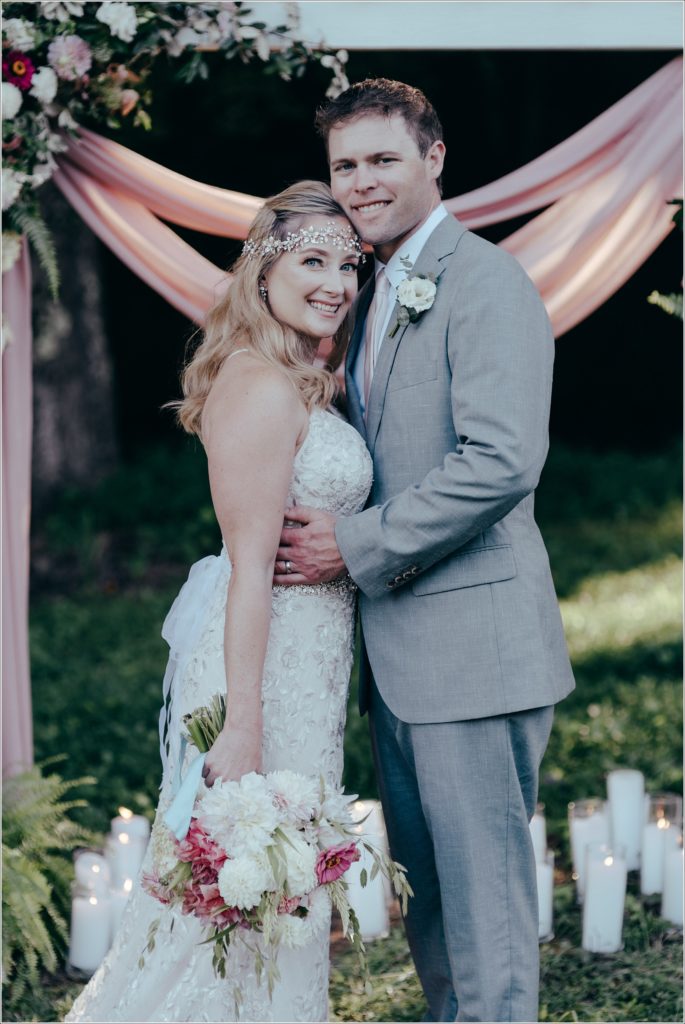 bride and groom pose with florals at vineyard