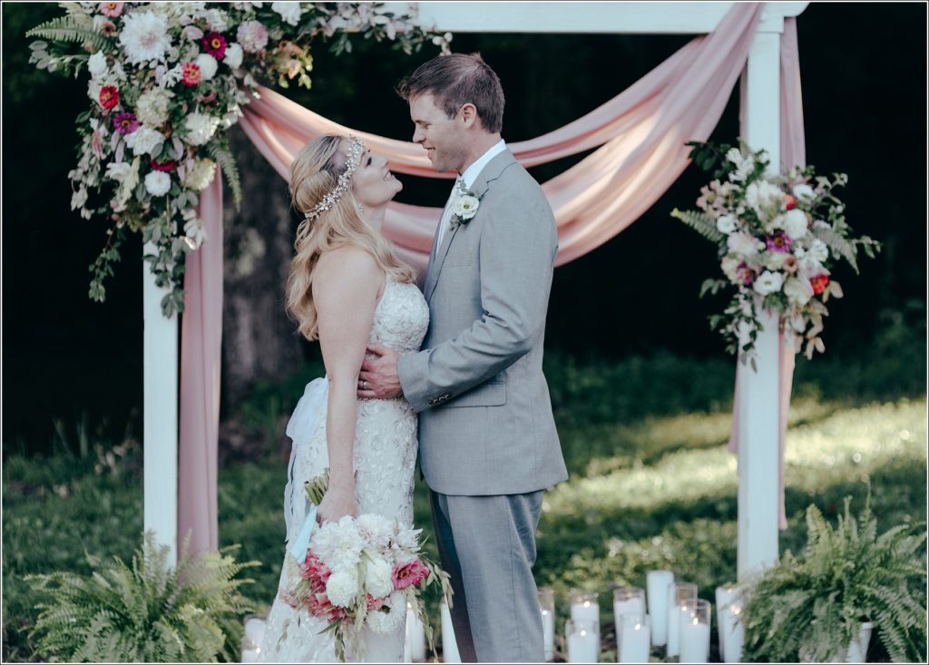 bride and groom pose with florals at vineyard