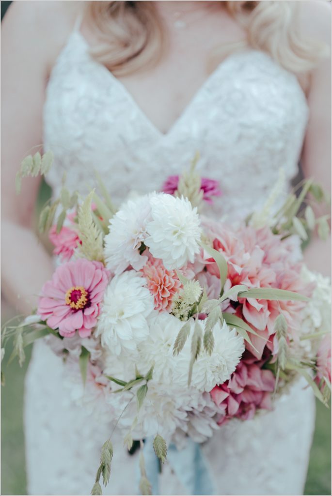 bride and groom pose with florals at vineyard