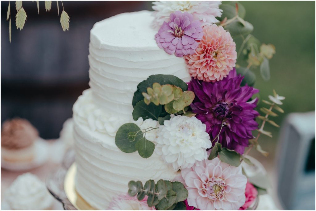 Wedding cake topped with flowers against a pink tablecloth