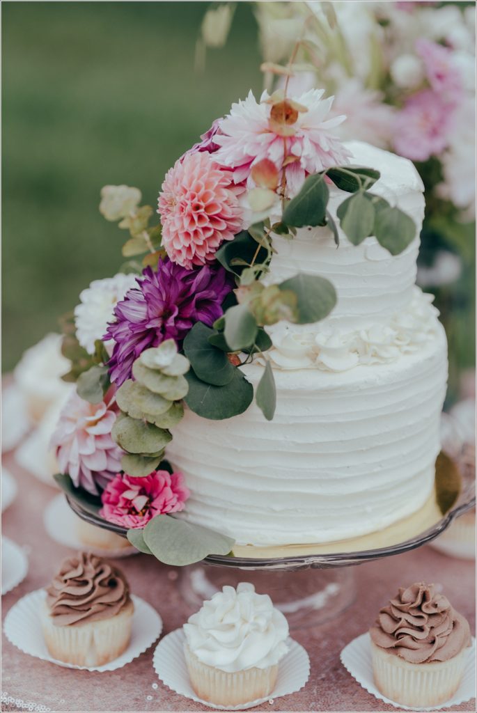 Wedding cake topped with flowers against a pink tablecloth