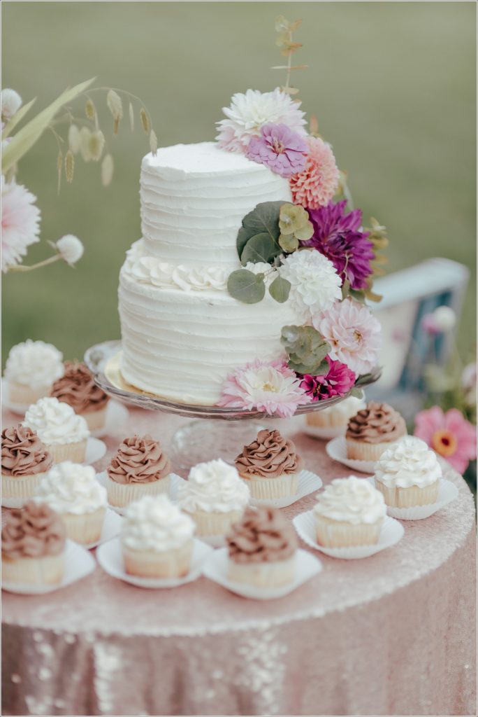 Wedding cake topped with flowers against a pink tablecloth