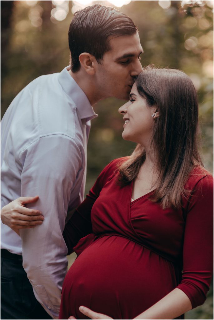 couple poses at sligo creek trail in burgundy maternity dress