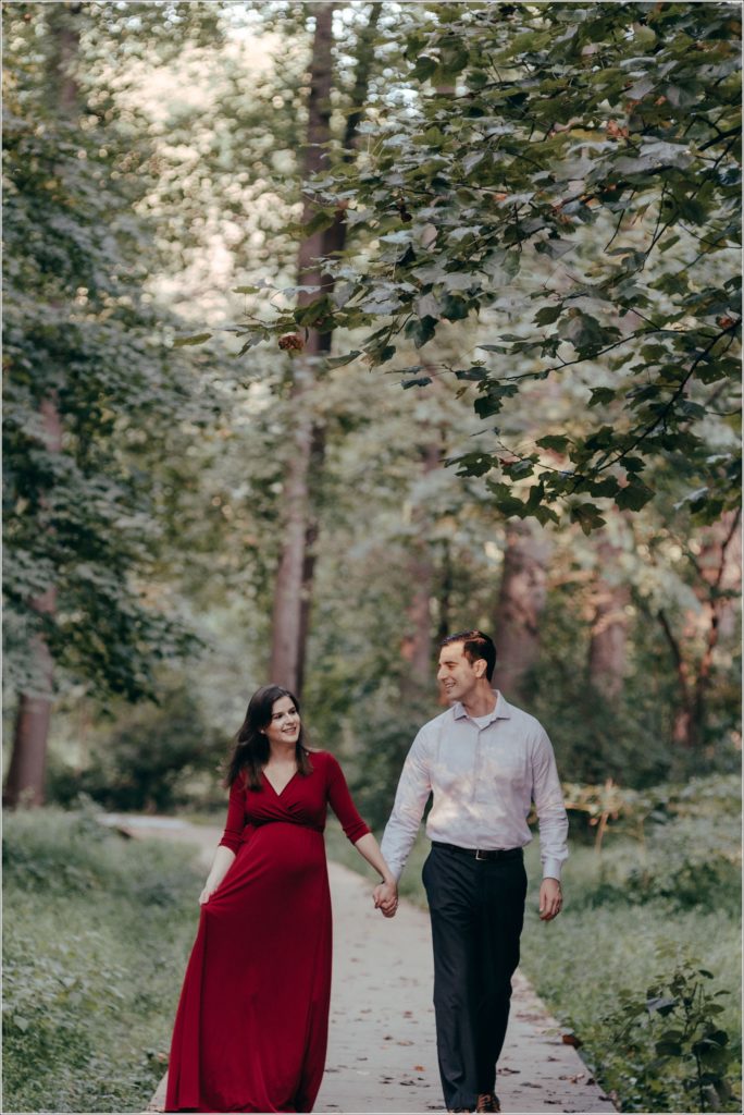 couple poses at sligo creek trail in burgundy maternity dress