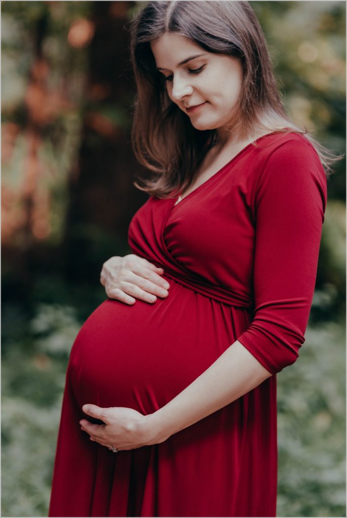 pregnant woman poses at sligo creek trail in burgundy maternity dress