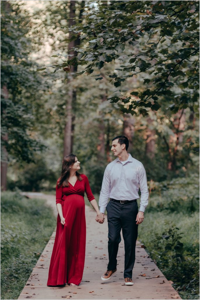 couple poses at sligo creek trail in burgundy maternity dress