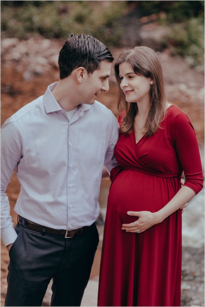 couple poses at sligo creek trail in burgundy maternity dress