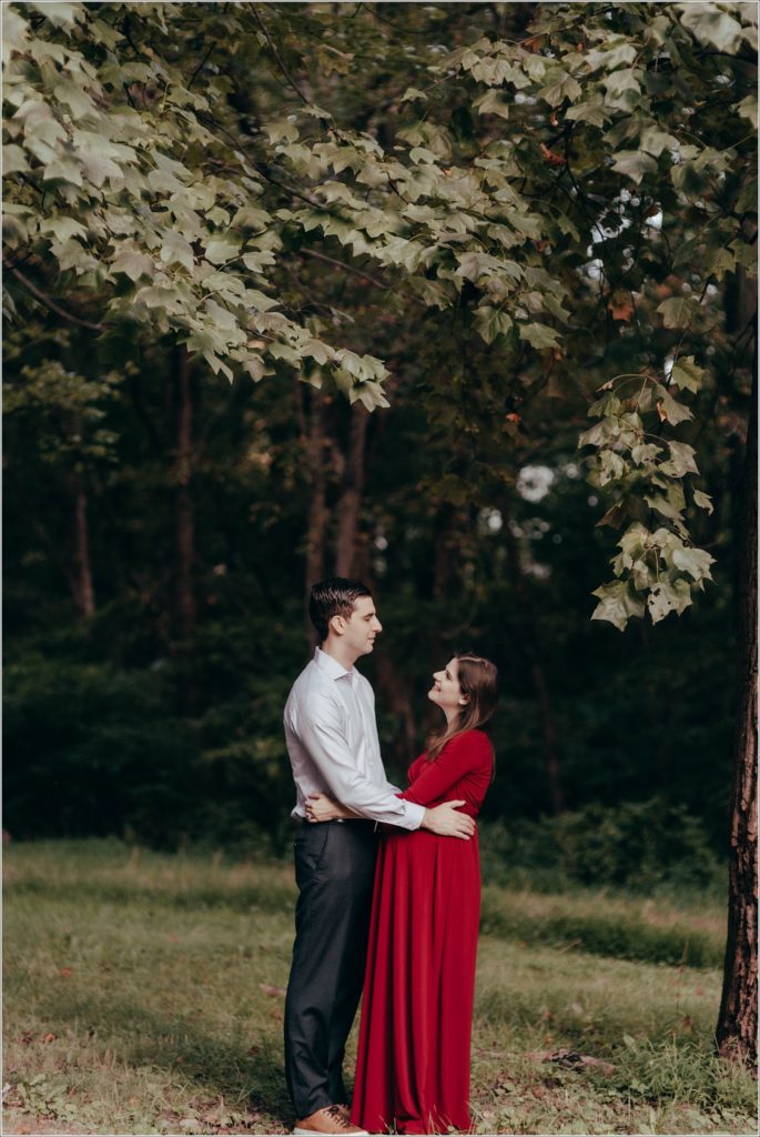 couple poses at sligo creek trail in burgundy maternity dress