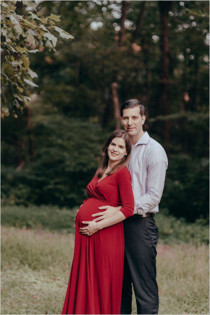 couple poses at sligo creek trail in burgundy maternity dress