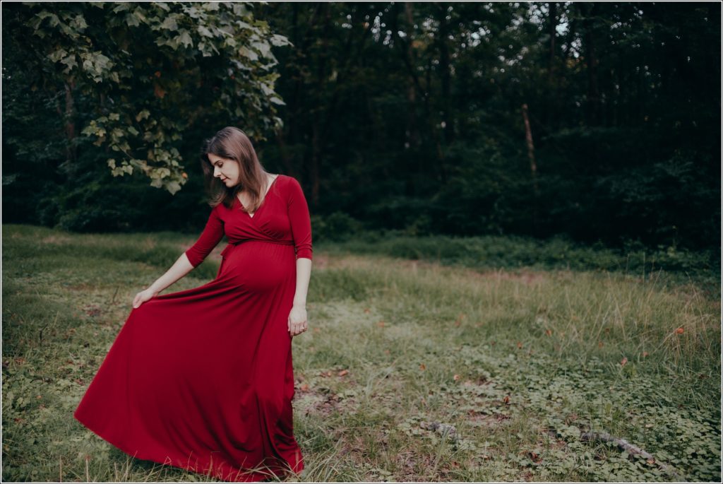 pregnant woman poses at sligo creek trail in burgundy maternity dress