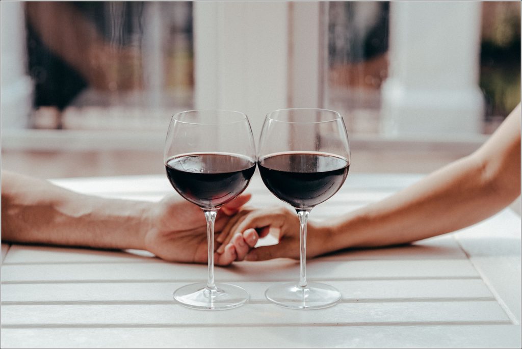 couple holds hands behind two glasses of wine at martha washington hotel and spa