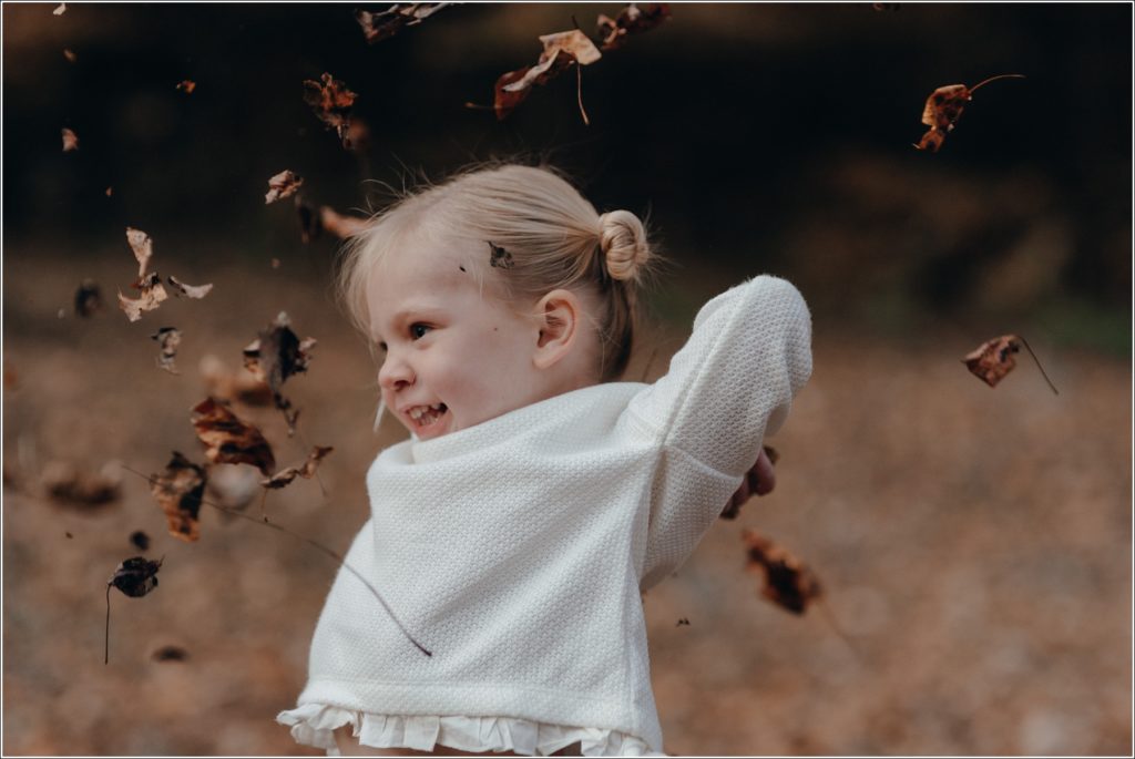 little girl throws fall leaves in abingdon virginia