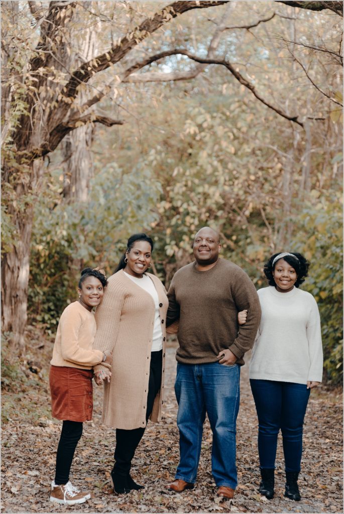 family poses for fall photos in golden and burnt orange against fall backdrop in frederick maryland