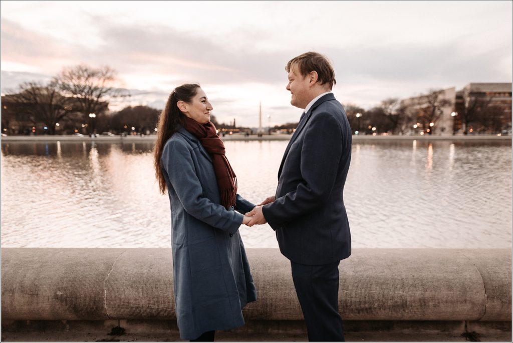 DC elopement couples poses holding hands in front of the water looking at each other