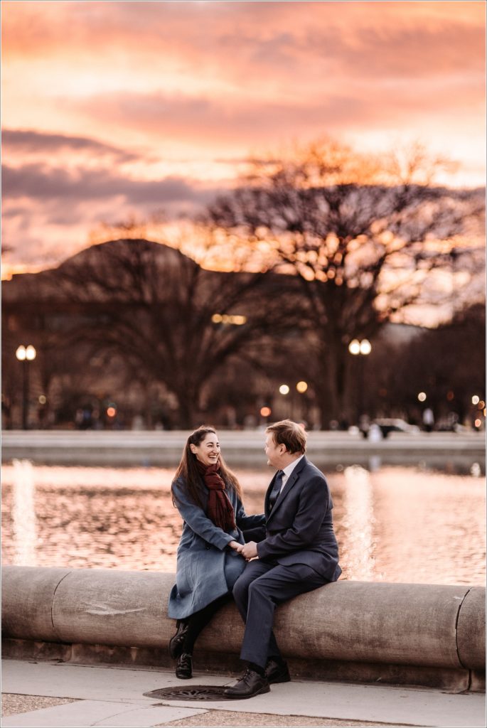 DC elopement couple poses by the water on Capitol Hill with orange and pink sunset behind them