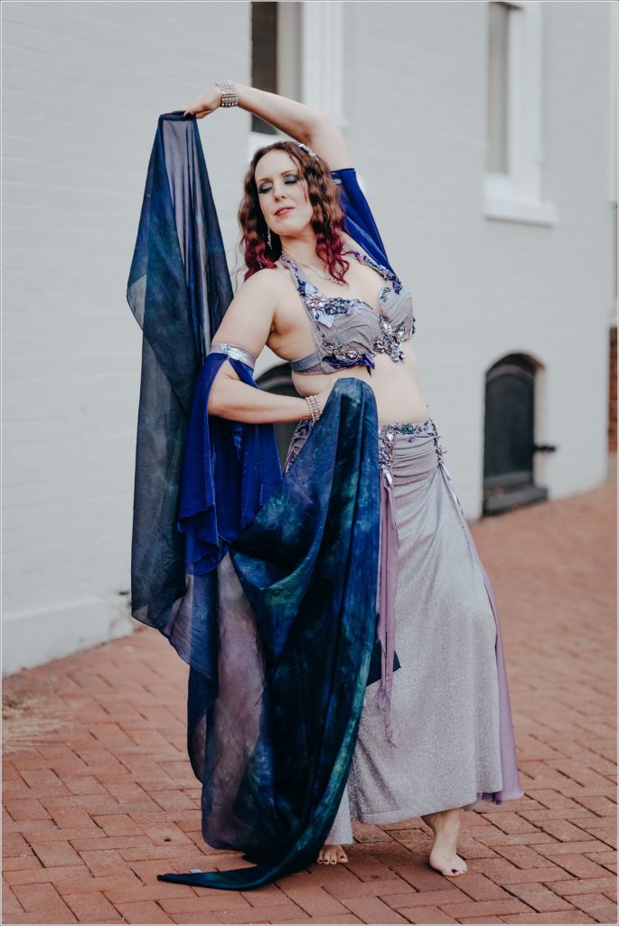 belly dancer photoshoot in blue and purple costume on red brick sidewalk