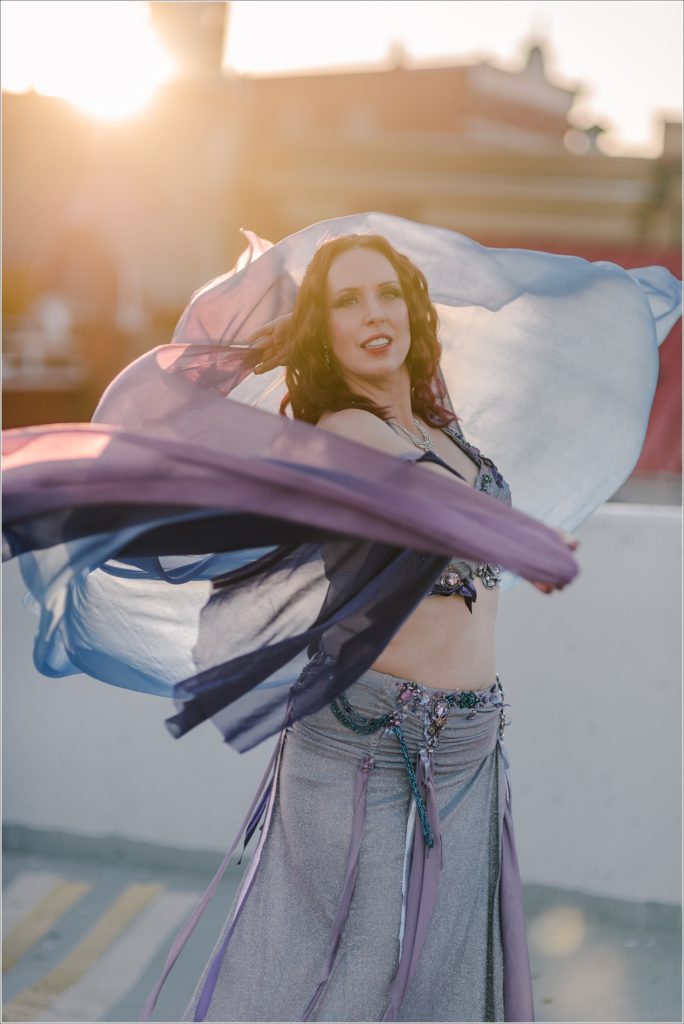 belly dancer photoshoot in blue and purple costume with sunset backdrop