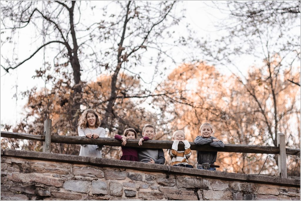 five kids pose over railing for family photos at catoctin furnace