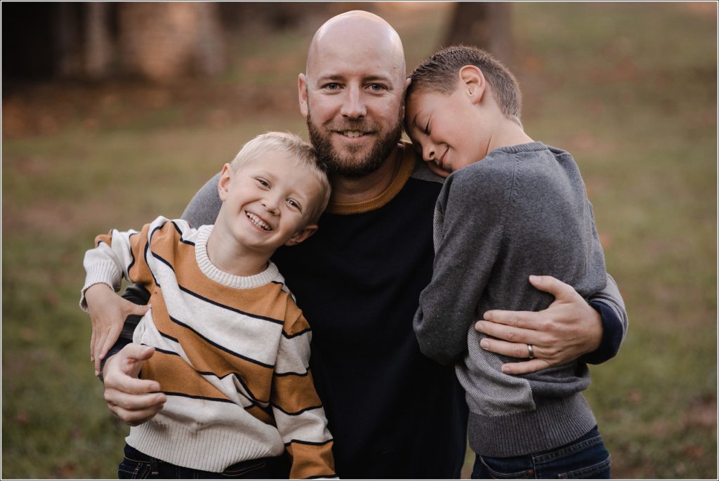two boys pose with their dad in the fall at catoctin furnace