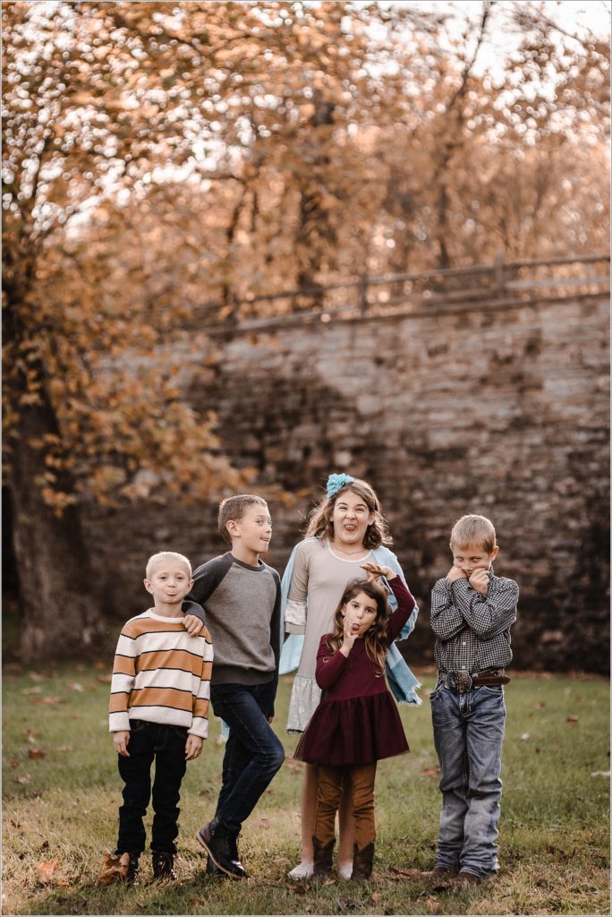 family poses for large family photos in the fall at catoctin furnace at sunset