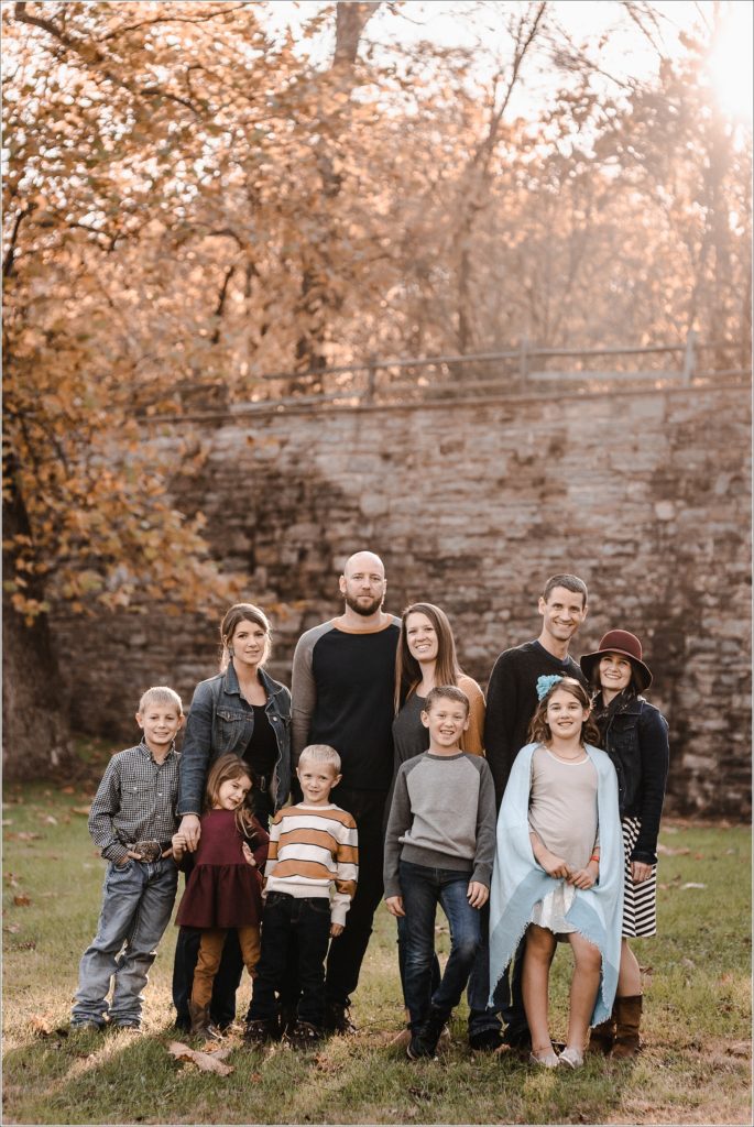 family poses for large family photos in the fall at catoctin furnace at sunset