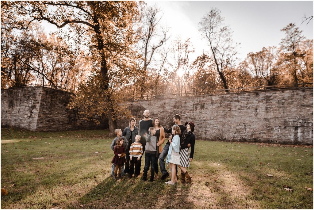 family poses for large family photos in the fall at catoctin furnace at sunset