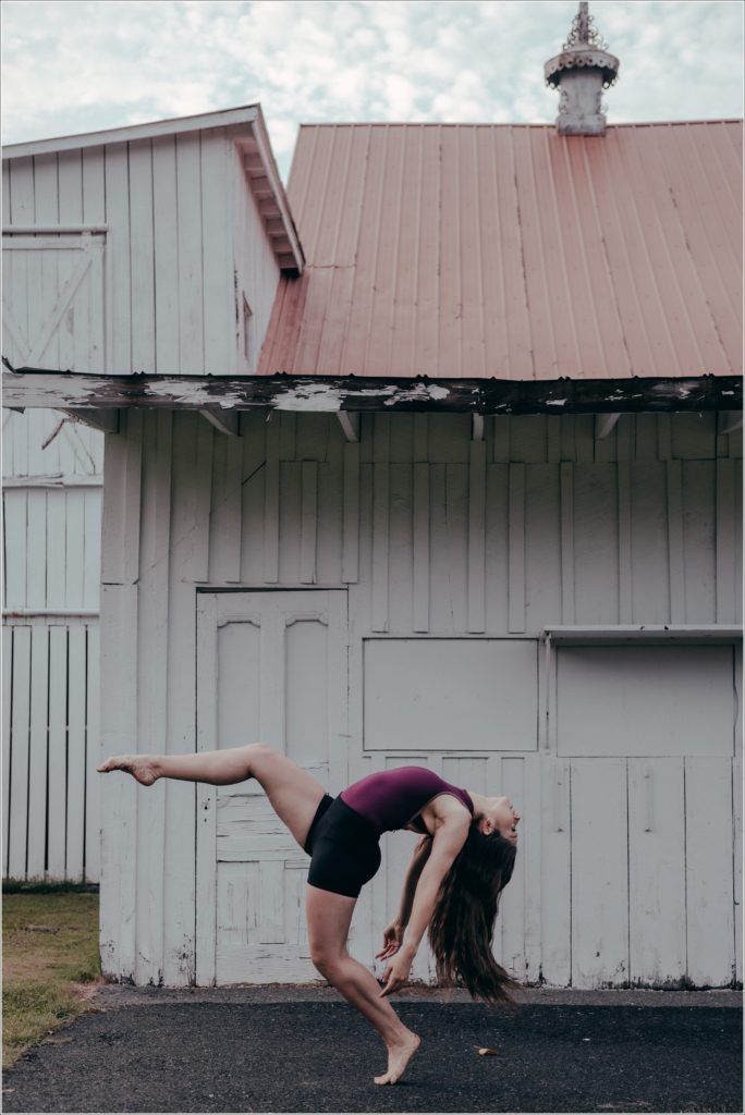 dc dancer in purple leotard and black shorts dances against white barn in Gaithersburg Maryland