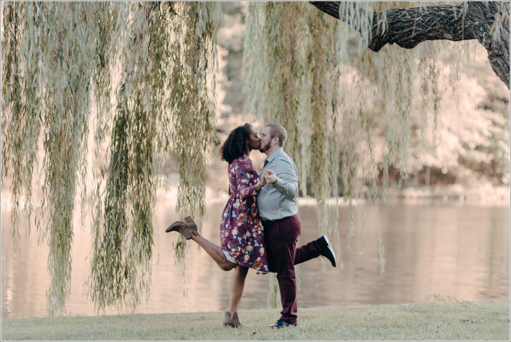 couple kisses under willow tree in floral dress in bowie md