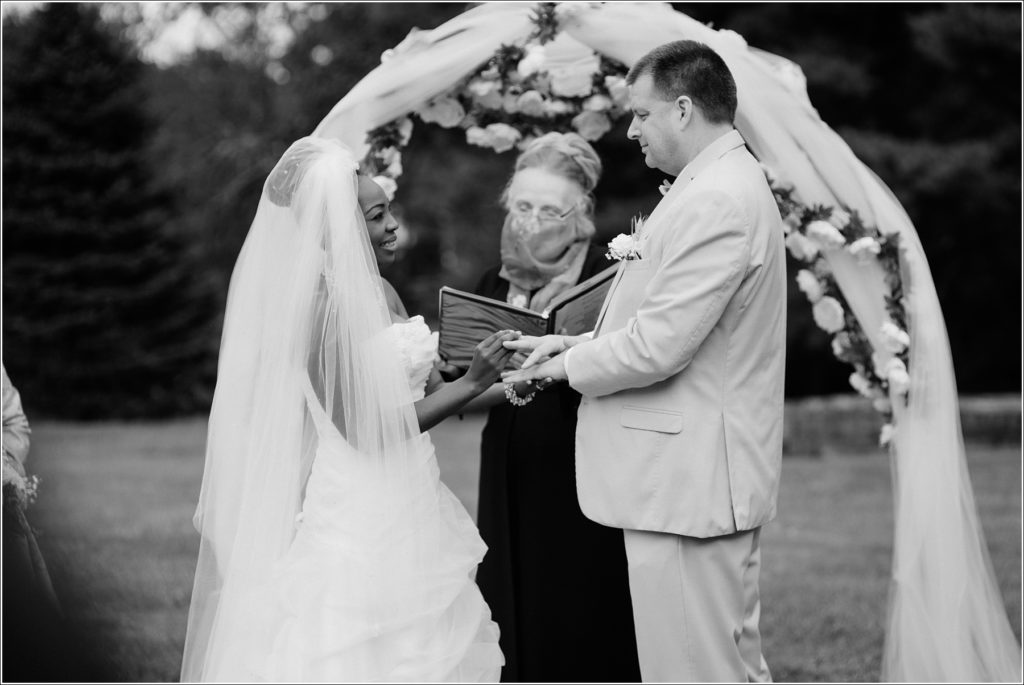 black and white photo of bride and groom exchanging rings
