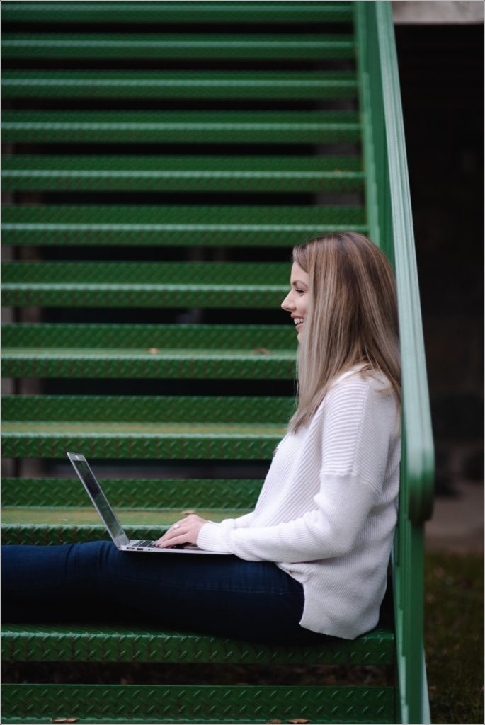arbonne consultant poses with laptop on green staircase for personal branding photography