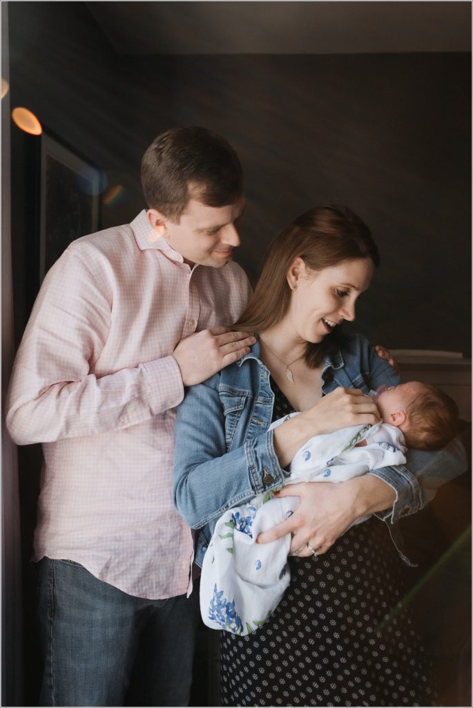 newborn held by parents in window light captured by maryland newborn photographer