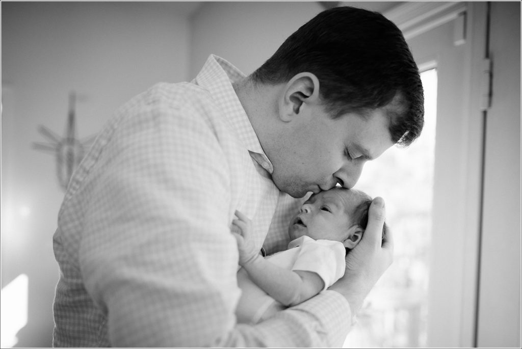 dad kisses newborn's forehead black and white image