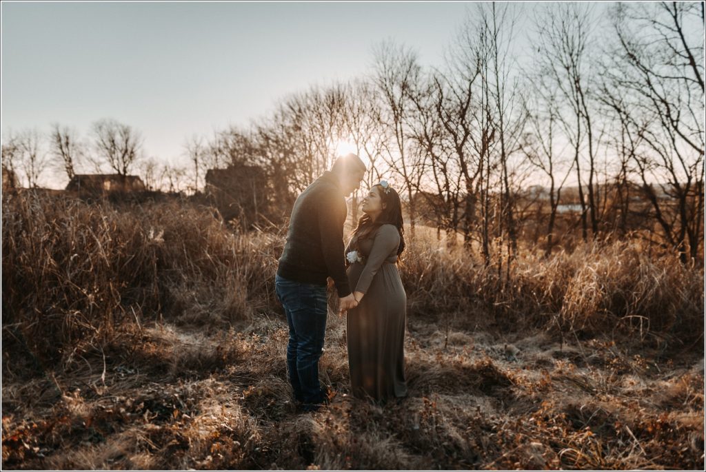 couple poses for maternity pics in frederick maryland at sunset