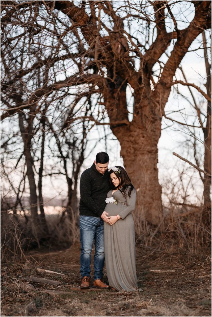 couple poses for maternity pics at sunset in middletown maryland in field