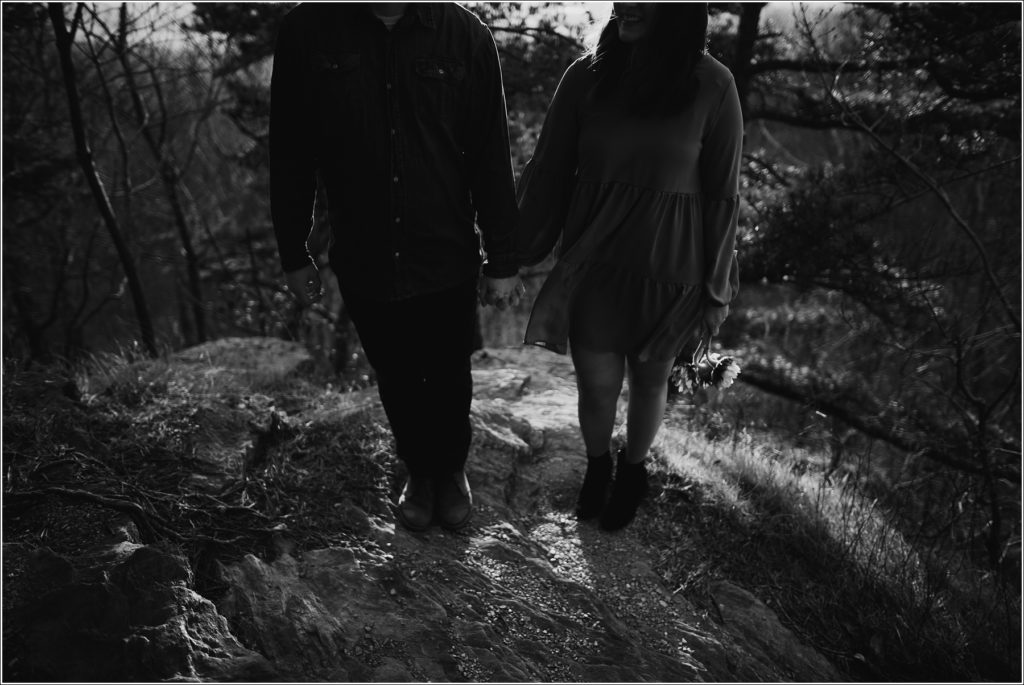 black and white photo of man and woman holding hands on rock