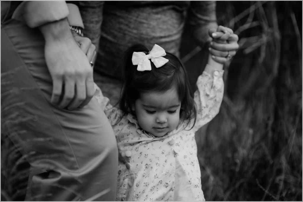 daughter plays with mom and dad in silver spring for family photos black and white photo