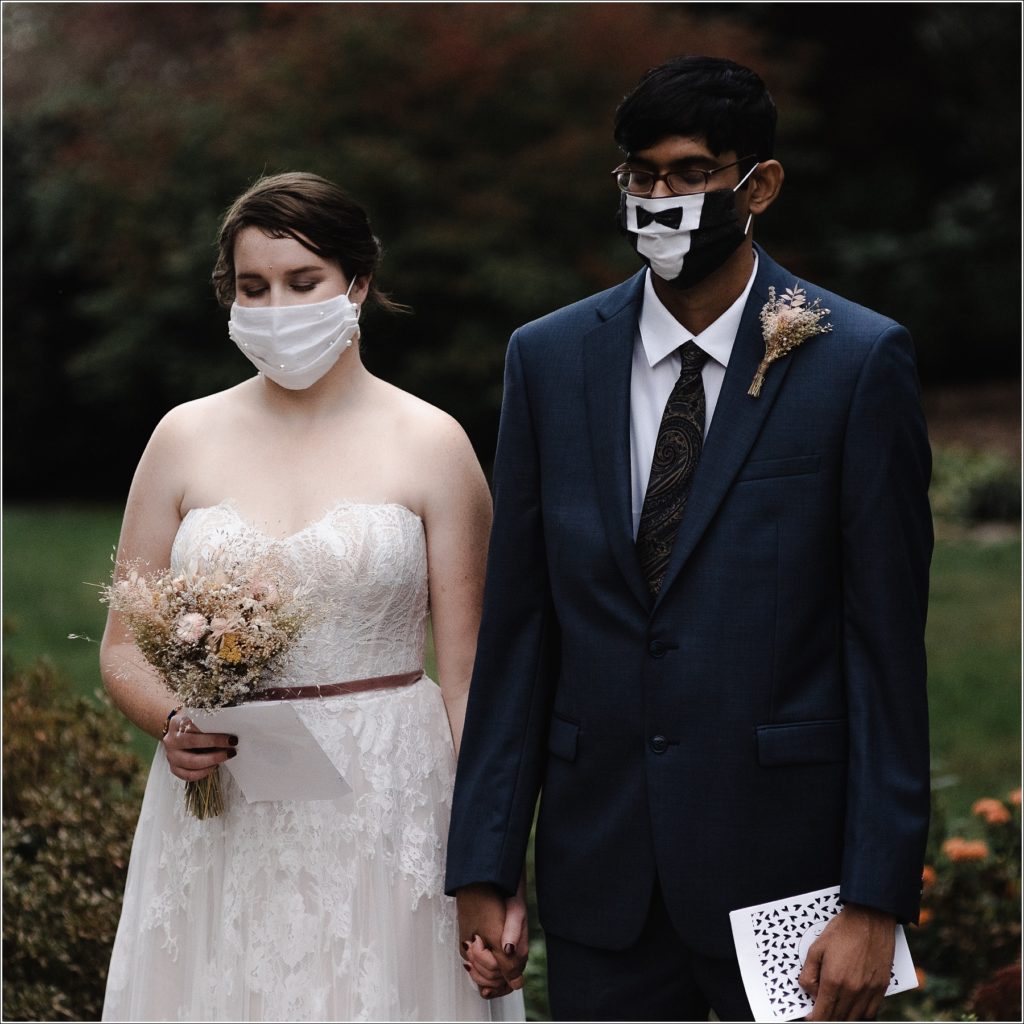 bride and groom hold hands with festive masks at their solomons island wedding