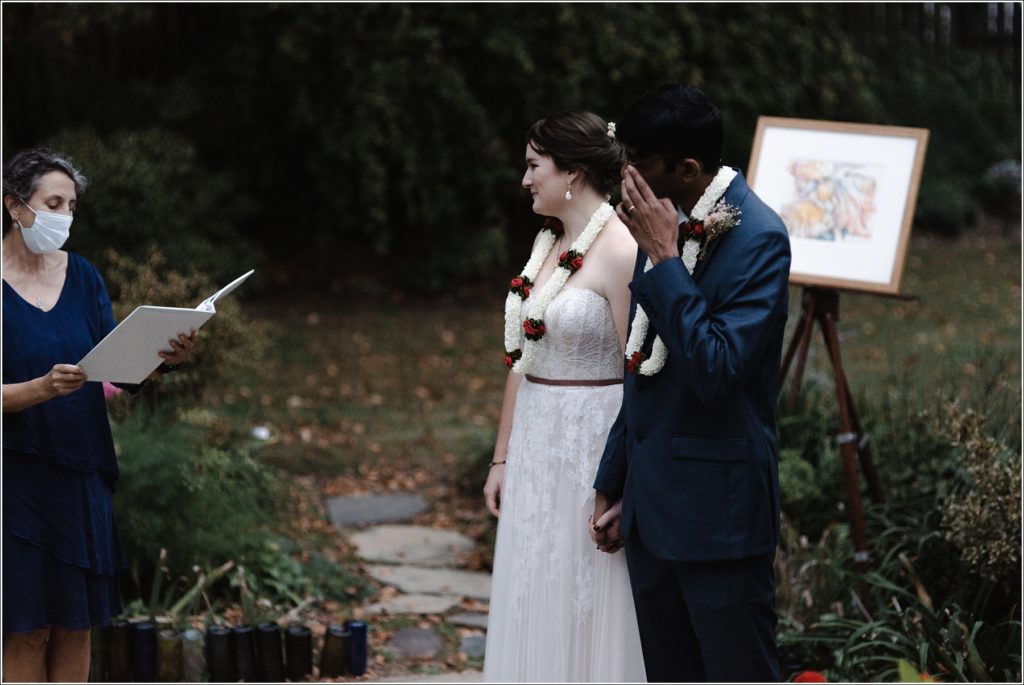 groom wipes a tear away as officiant reads