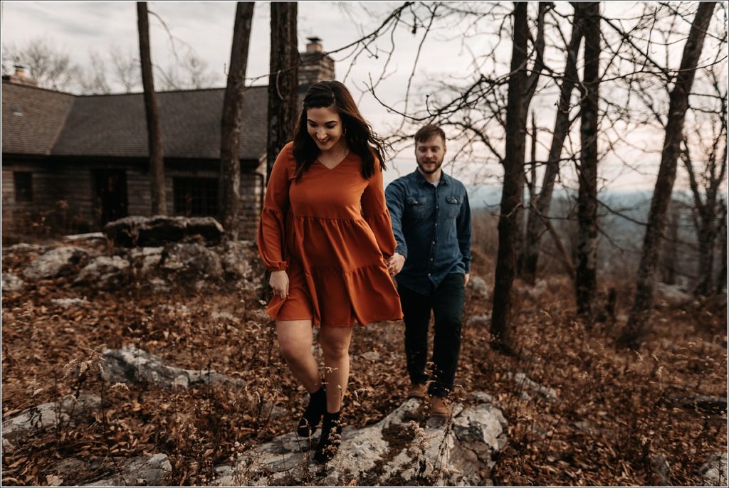 couple walks over rocks at middletown overlook photoshoot location holding hands